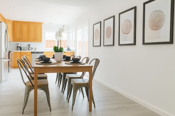 Una cocina moderna con armarios de madera, una mesa de comedor con sillas y una planta en maceta.