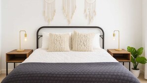 A bedroom with a bed, two bedside tables, a wall-mounted dreamcatcher, and a potted plant. - Marbella Lane - 4BR Alluring Home (Union City)