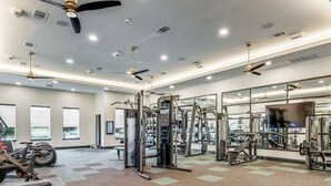 A gym with ceiling fans, exercise equipment, and large windows. - Workerfriendly,washer/dryer, Gym,pool, A+ Location (Sherman)