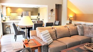 A modern living room with a sofa, a dining table, and a kitchen in the background. - Lone Eagle Landing 2 (Bend)