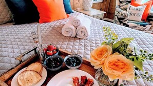A neatly made breakfast tray with toast, eggs, and bacon on a wooden tray, placed on a bed with a quilted cover and pillows. - Lakefront Hot Tub Canoes Game Room Wood FP (Gouldsboro)