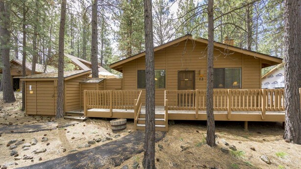 A cabin with a porch, a small shed, and a covered outdoor area. - Timber 12 (Bend)