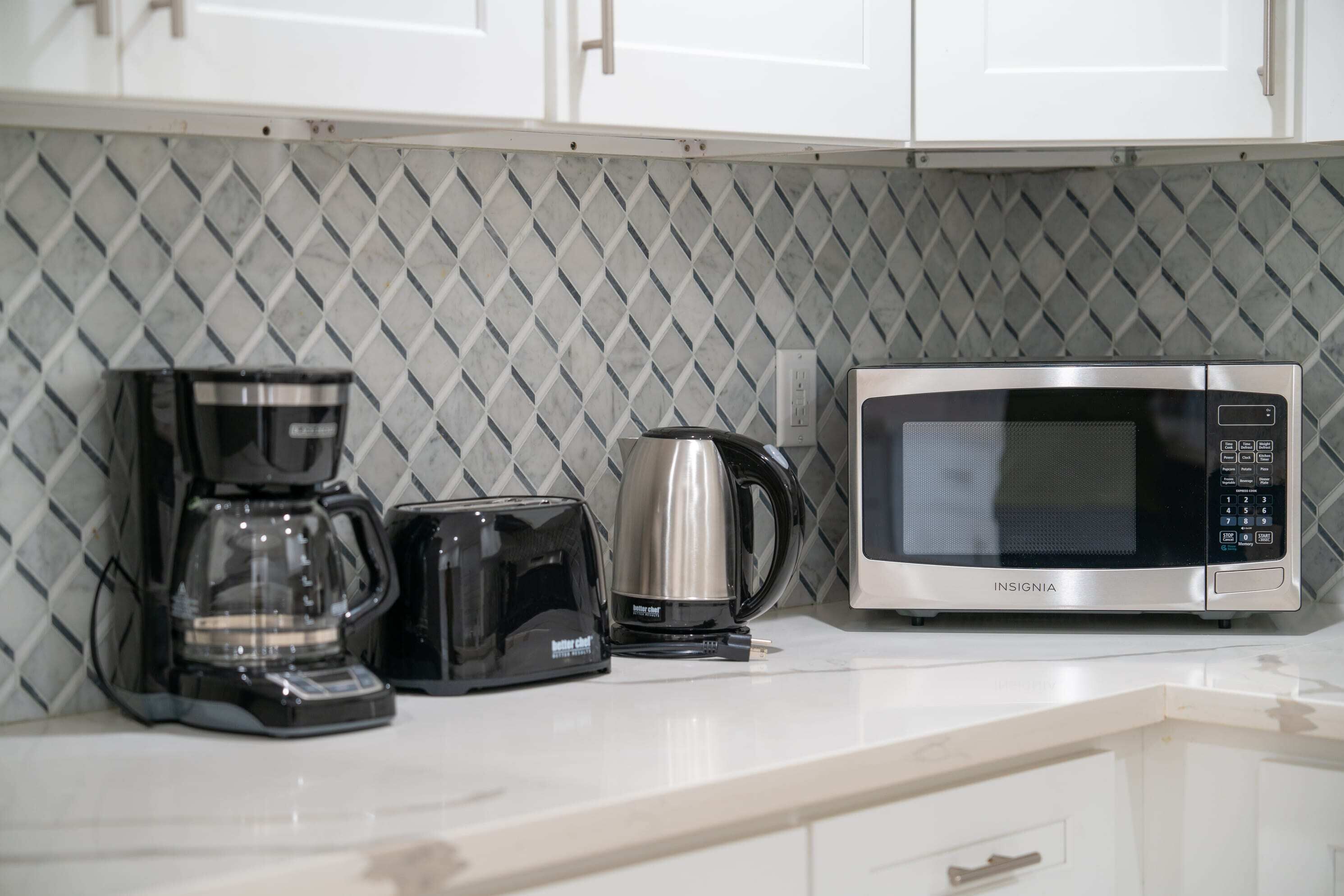 A kitchen with a coffee maker, toaster, and microwave on the counter.