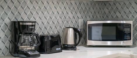 A kitchen with a coffee maker, toaster, and microwave on the counter.