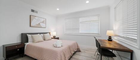 A bedroom with a bed, bedside tables, a desk, and a chair.