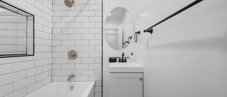 Un baño moderno con bañera, ducha, lavamanos y espejo.