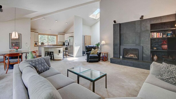 Un espacio habitable amplio con chimenea, un sofá, una mesa de centro y una cocina al fondo.