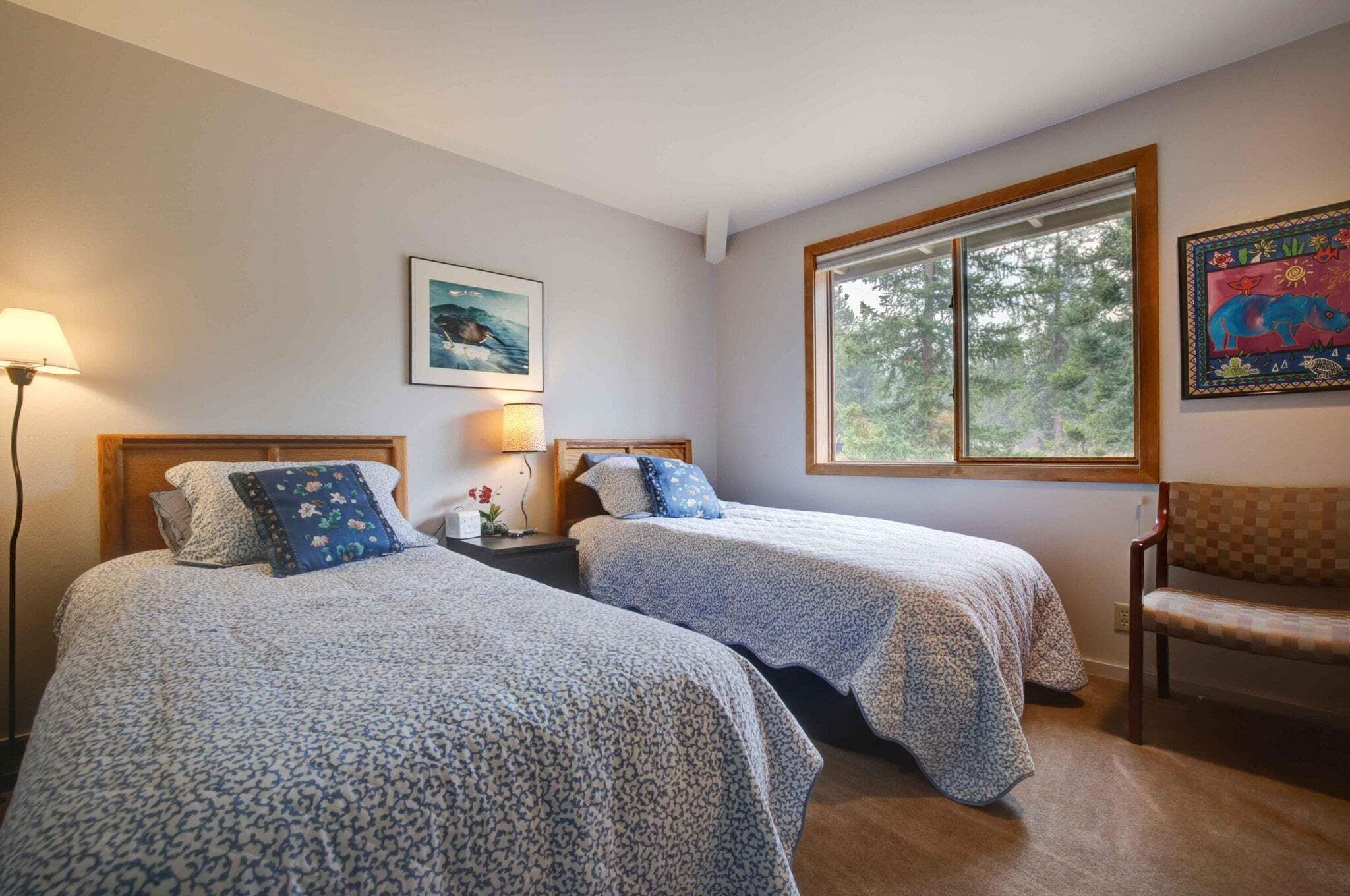 Een slaapkamer met twee bedden, een raam, een stoel en een lamp.