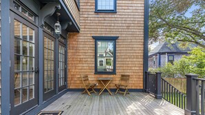 A wooden deck with a black metal railing, a small table, and two chairs. - The Royce on Spring - High-end Family Getaway in Newport (Newport)