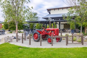 Un tracteur rouge est garé devant un bâtiment doté d’un patio couvert.