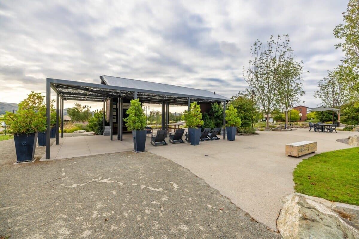 A covered outdoor seating area with chairs and potted plants.