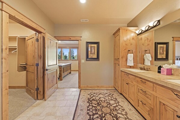 A spacious bathroom with wooden cabinets, a large mirror, and a walk-in closet. - Wallowa 22 (Bend)