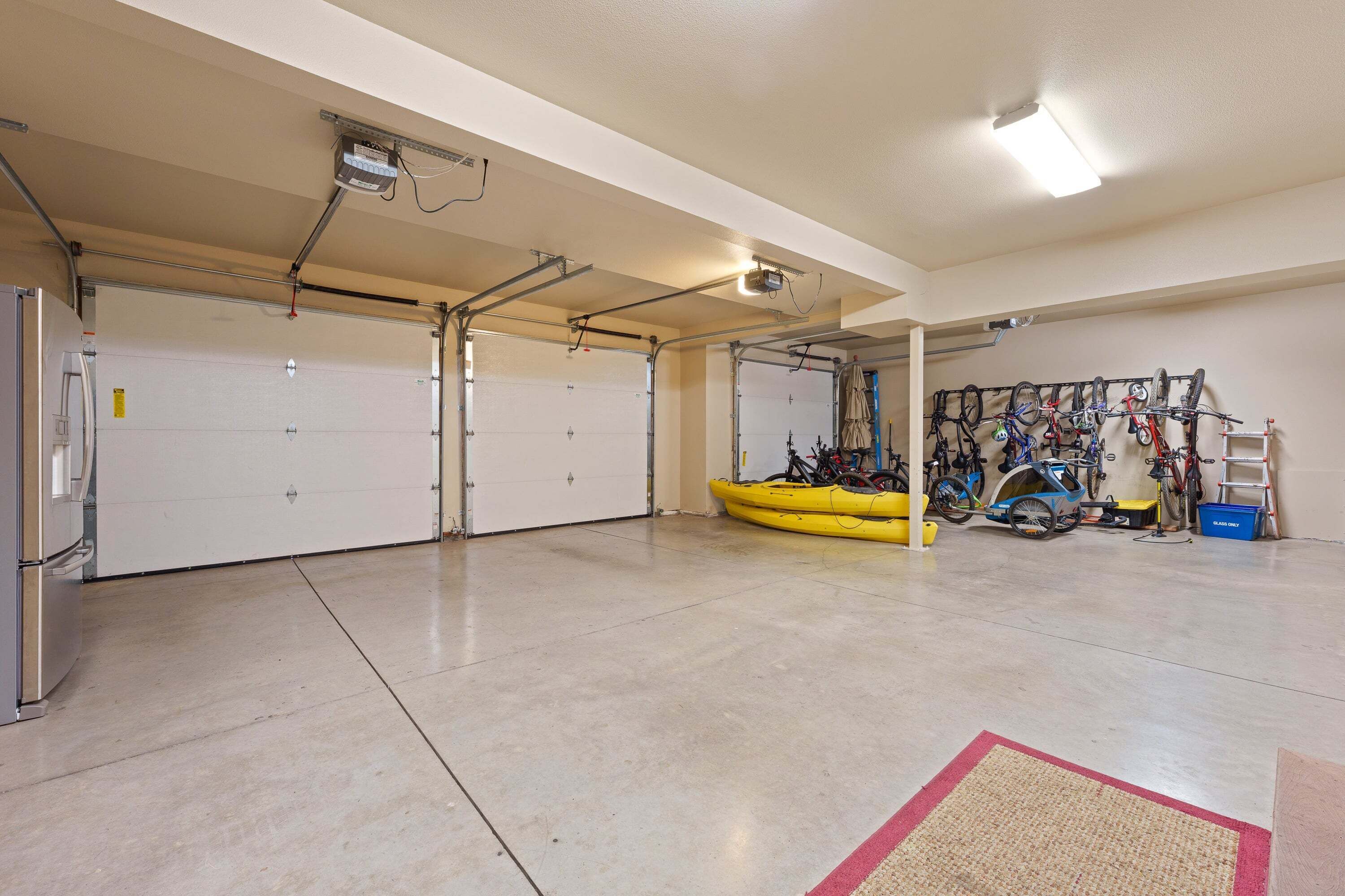 Un garage avec deux portes blanches, un kayak jaune et un porte-vélo fixé au mur.