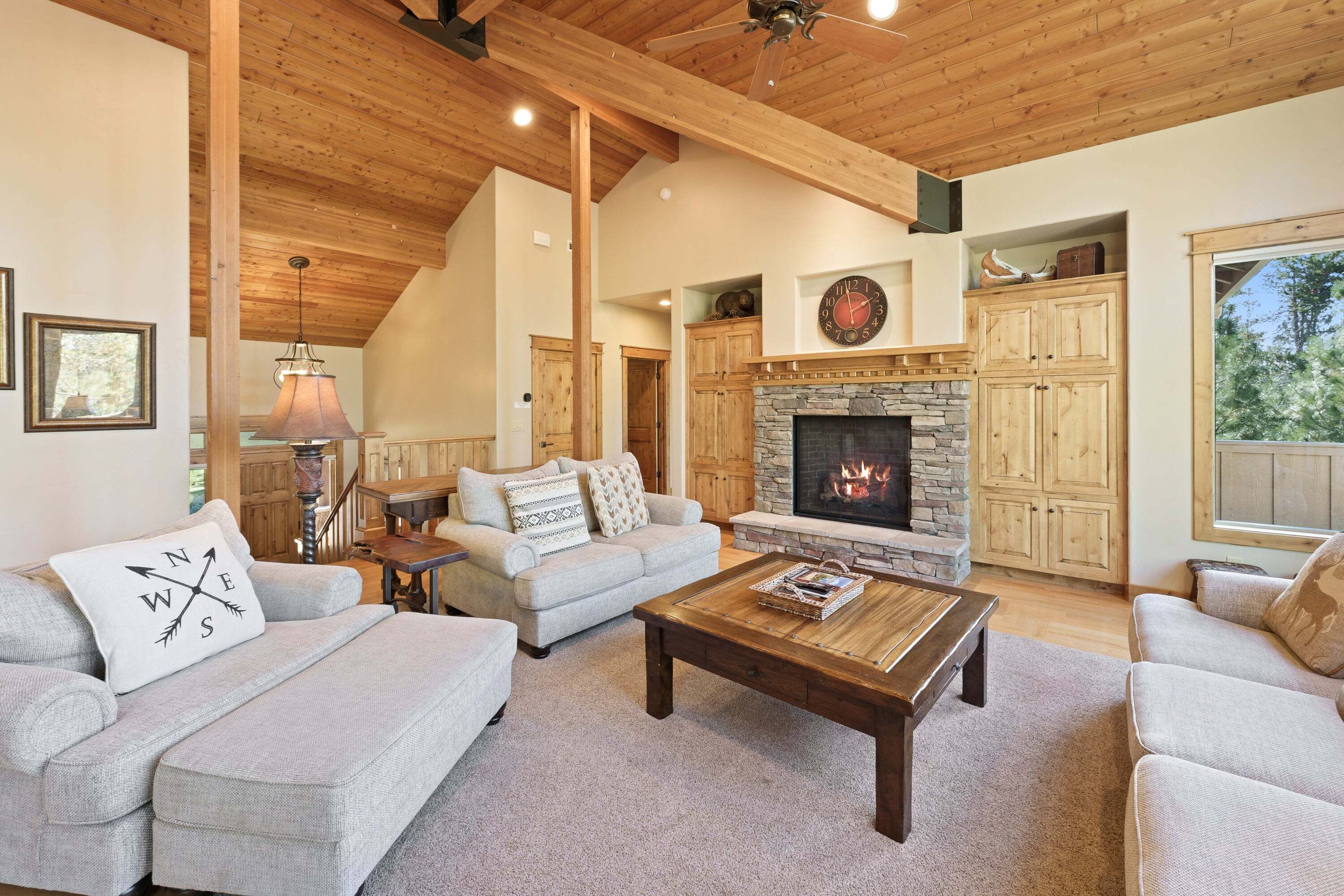 A spacious living room with a fireplace, wooden ceiling beams, and a cozy seating area.