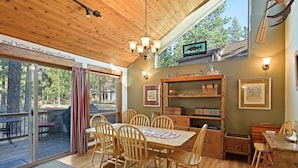 A wooden dining area with a table and chairs, a chandelier, and a bookshelf. - Tamarack 8 (Bend)