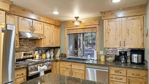 A kitchen with wooden cabinets, a stainless steel refrigerator, a stove, and a dishwasher. - Tamarack 8 (Bend)