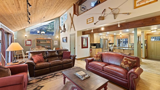A spacious living area with leather sofas, a coffee table, and a kitchen in the background. - Tamarack 8 (Bend)