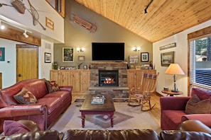 A cozy living room with a fireplace, leather sofas, a flat-screen TV, and wooden ceilings. - Tamarack 8 (Bend)