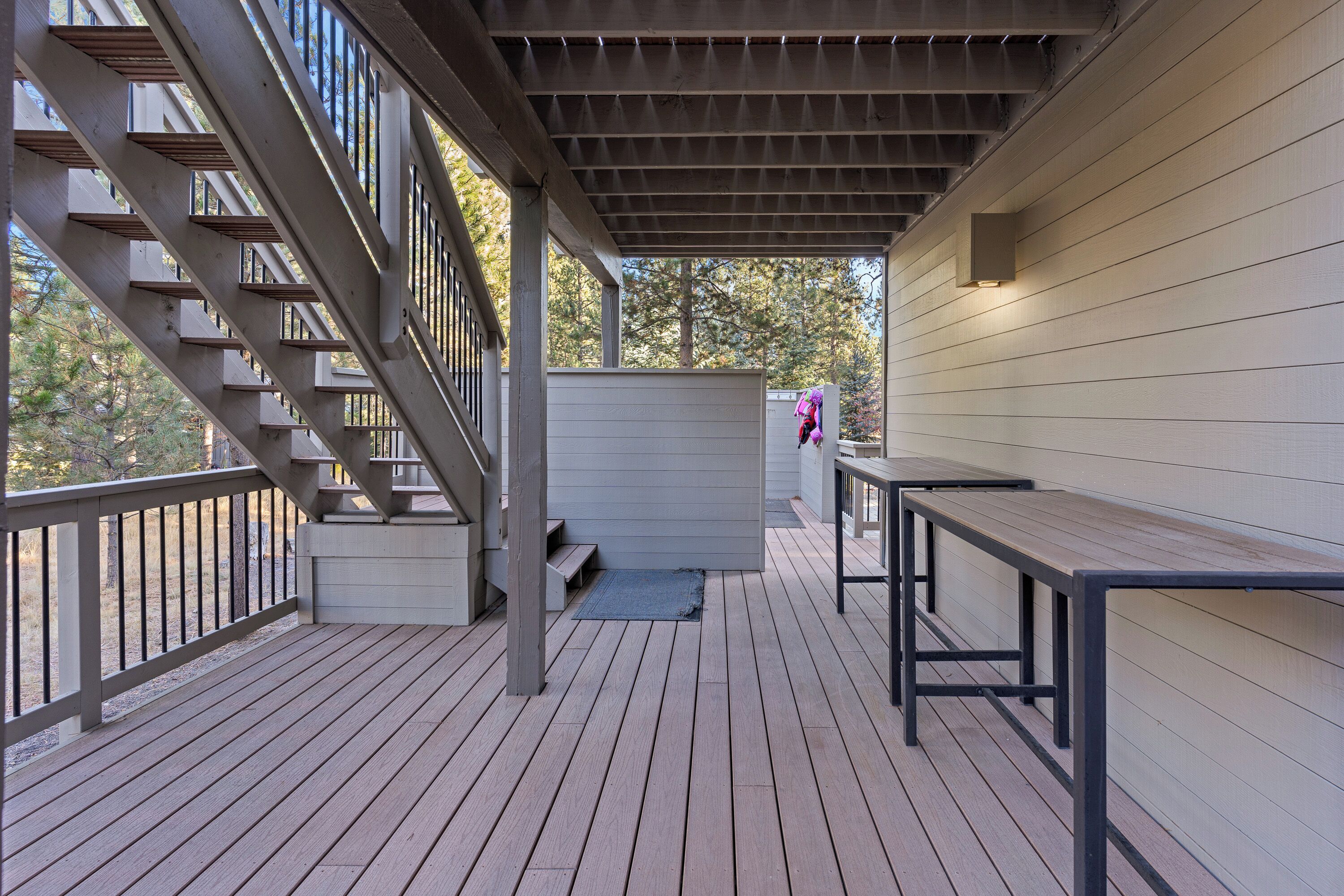 Une terrasse en bois avec un escalier, un banc et un luminaire fixé au mur.