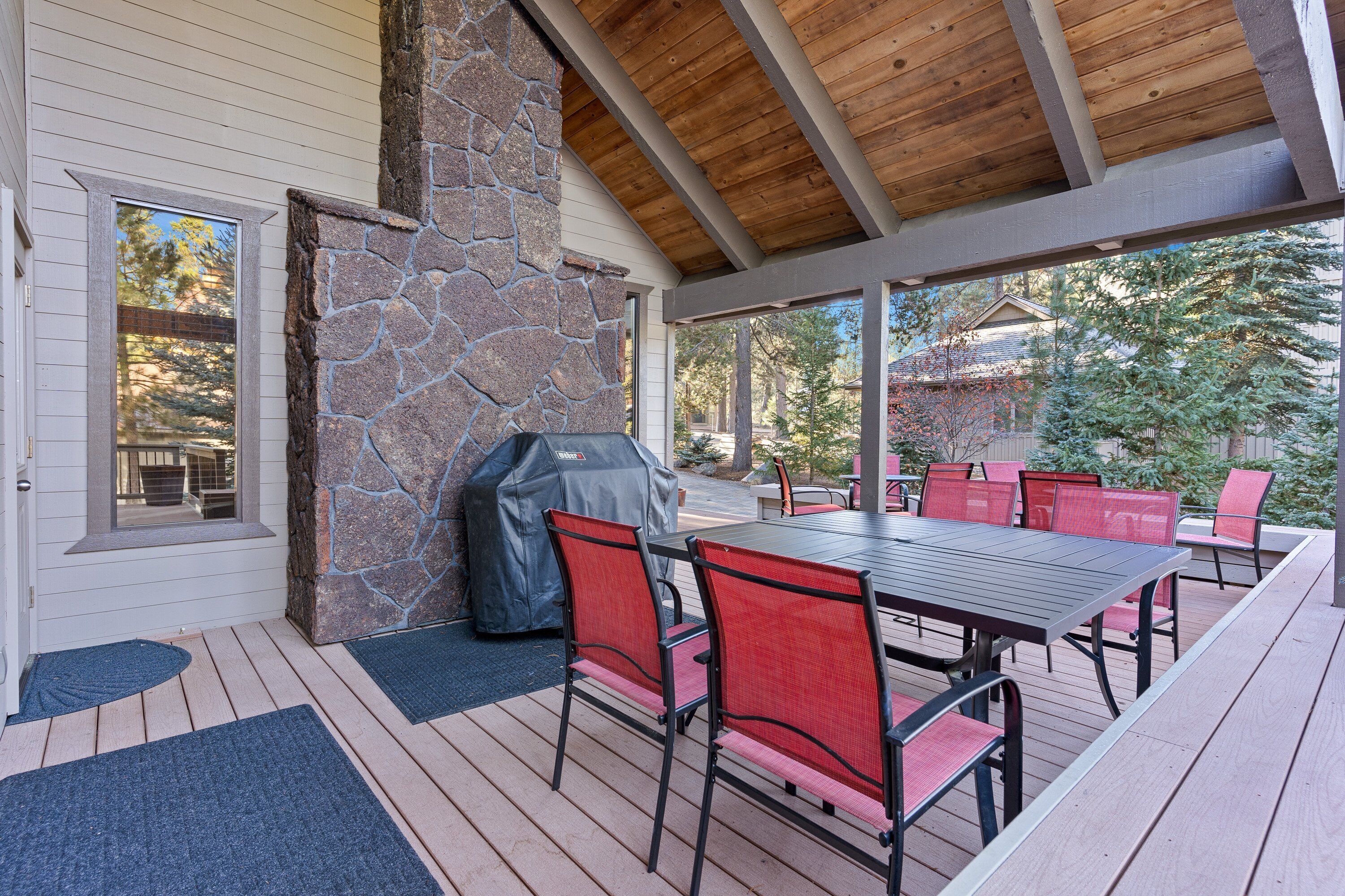 An outdoor patio with a stone fireplace, a covered seating area, and a table with chairs.