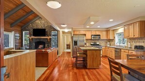 Une cuisine moderne avec une cheminée en pierre, des armoires en bois et un grand îlot central.
