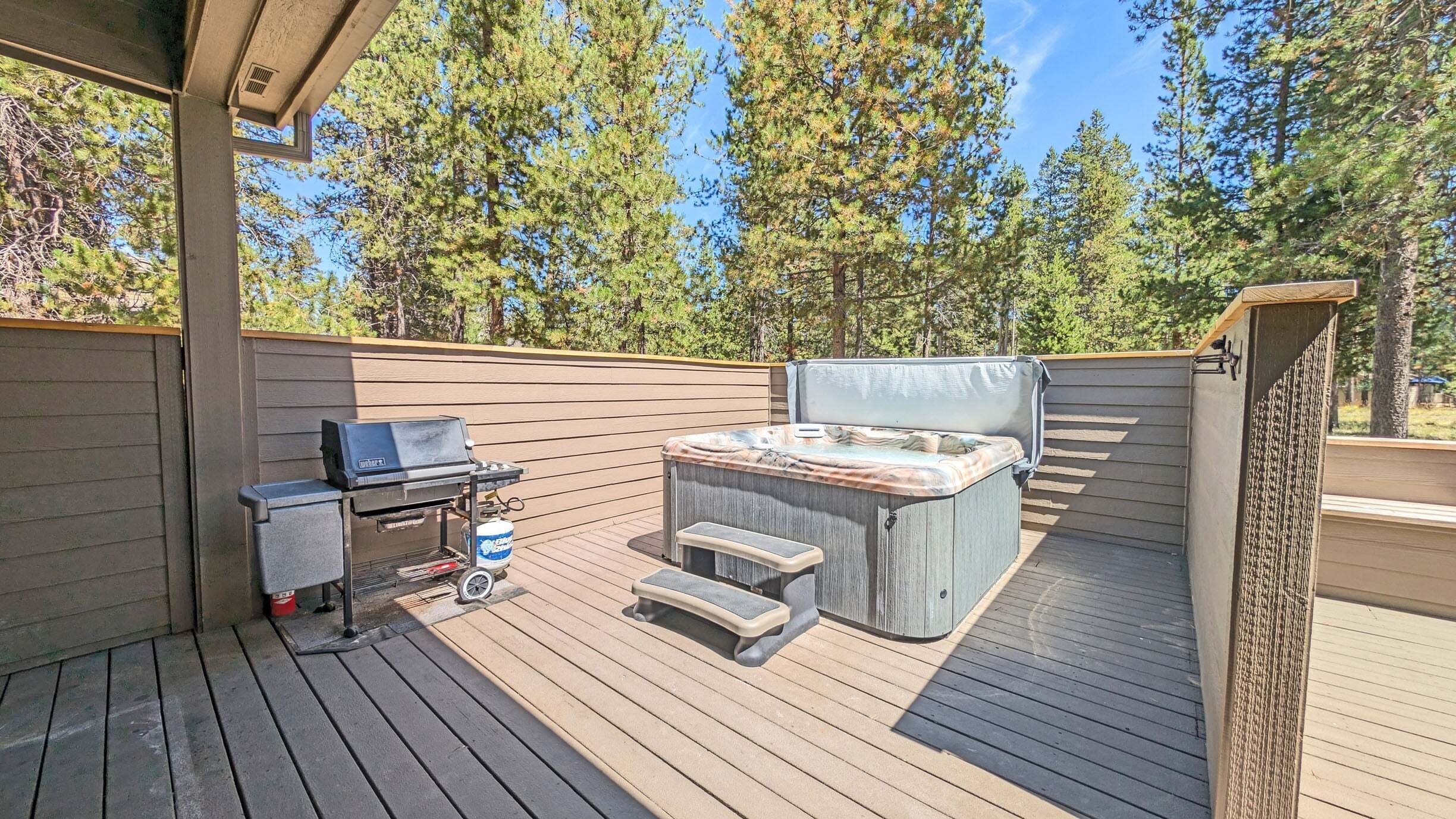 An outdoor deck with a hot tub, a grill, and a seating area.