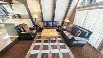 A living room with a black leather sofa set, a wooden coffee table, and a checkered rug.