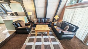 A living room with a black leather sofa set, a wooden coffee table, and a checkered rug. - Trapper 11 (Bend)