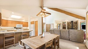 A spacious kitchen with wooden cabinets, a dining table, and a stone fireplace. - Tokatee 1 (Bend)