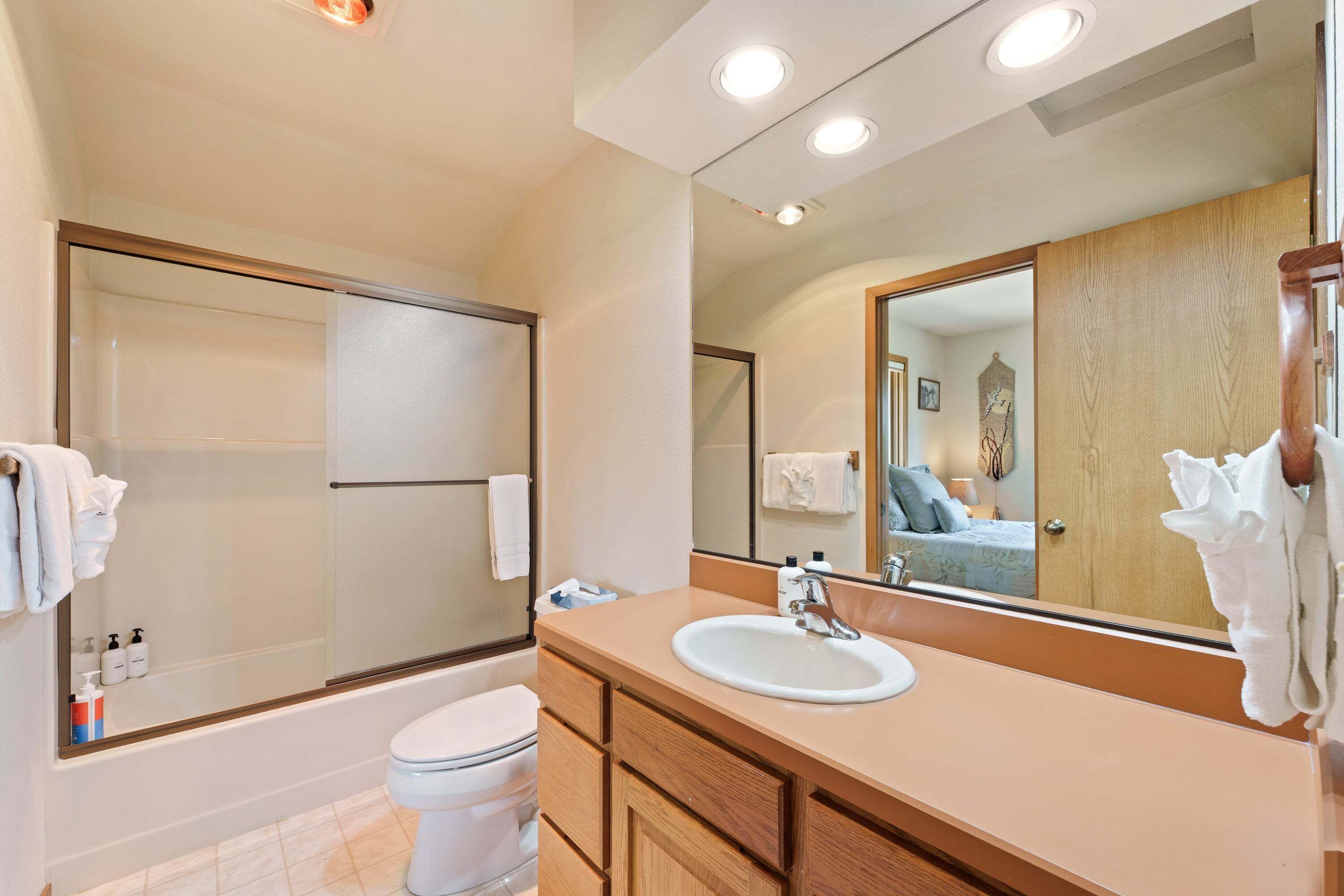 A modern bathroom with a bathtub, toilet, sink, and large mirror.