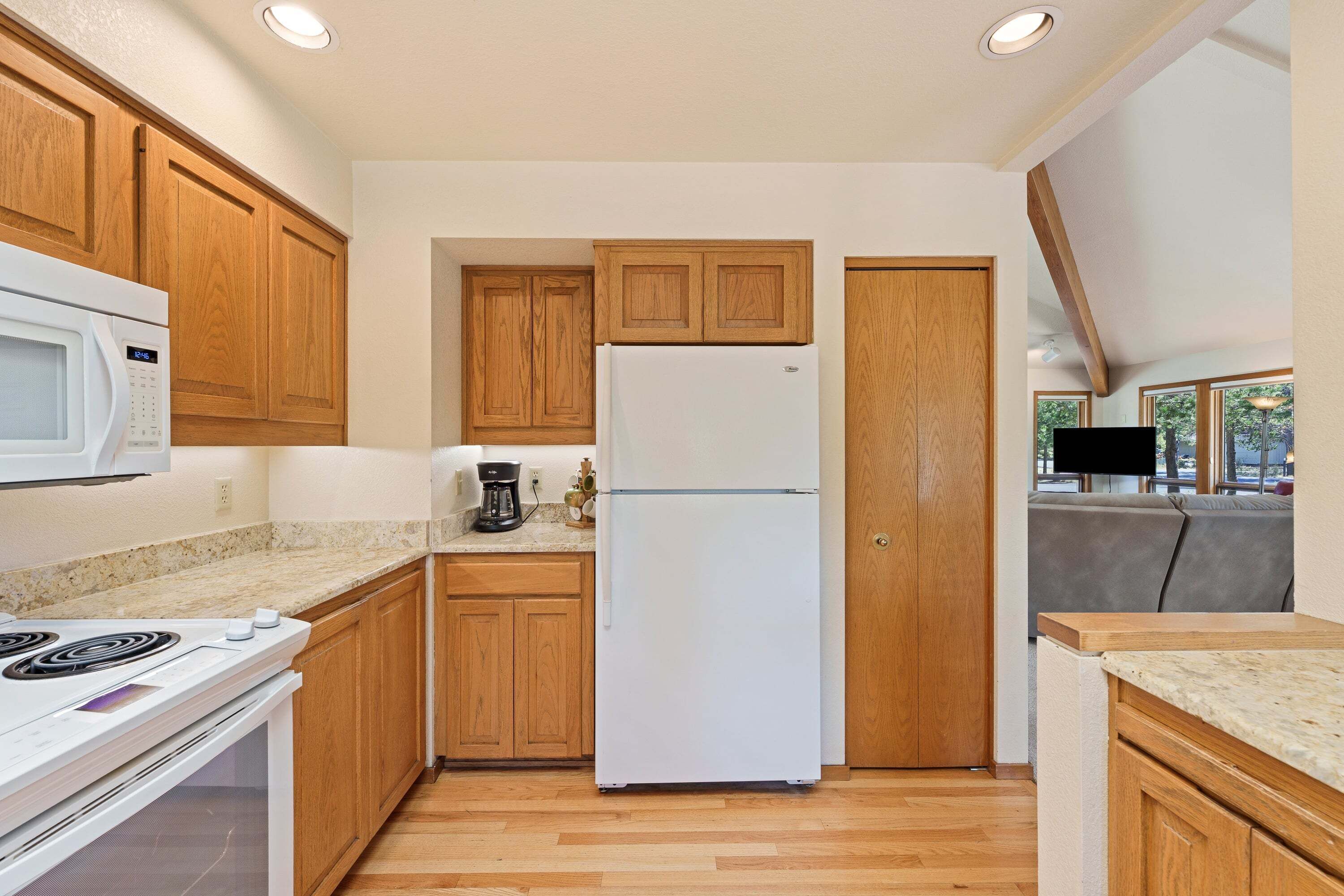 A kitchen with wooden cabinets, a white refrigerator, a microwave, and a stove.