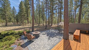 A deck with outdoor furniture, a fire pit, and a view of a forested area. - Pine Cone 3 (Bend)