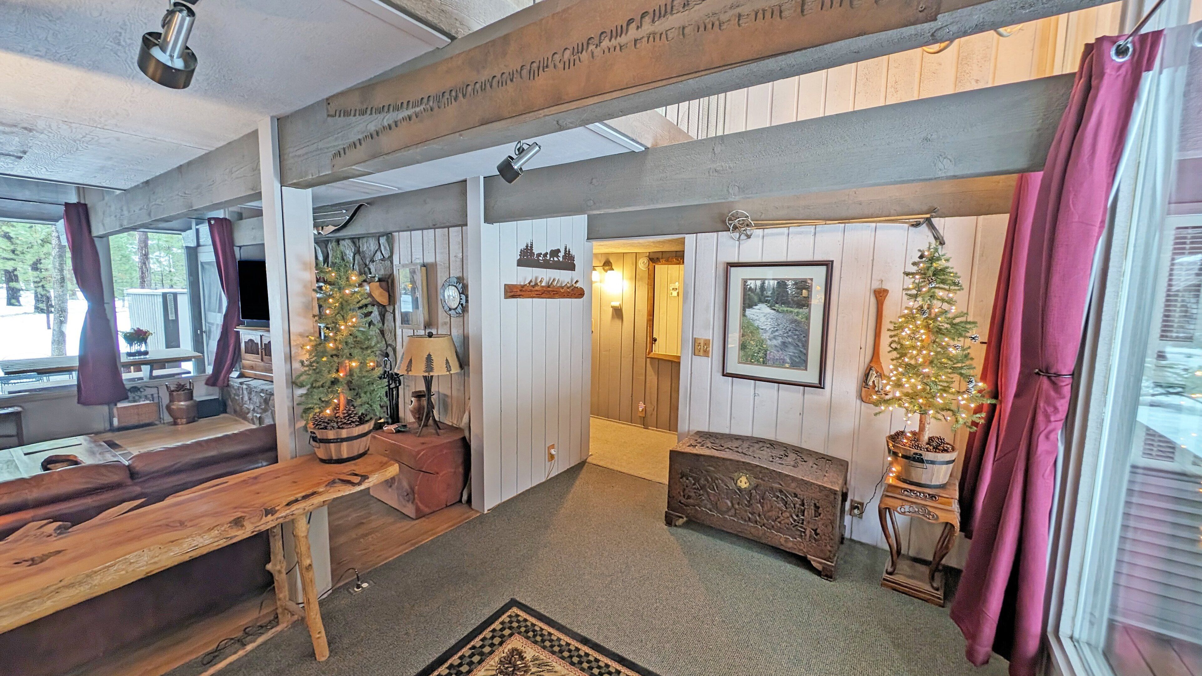 A cozy interior with a wooden bench, a Christmas tree, a fireplace, and a framed picture on the wall.