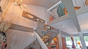 A multi-level wooden interior with a staircase, a chandelier, and a dining area. - Pine Cone 3 (Bend)