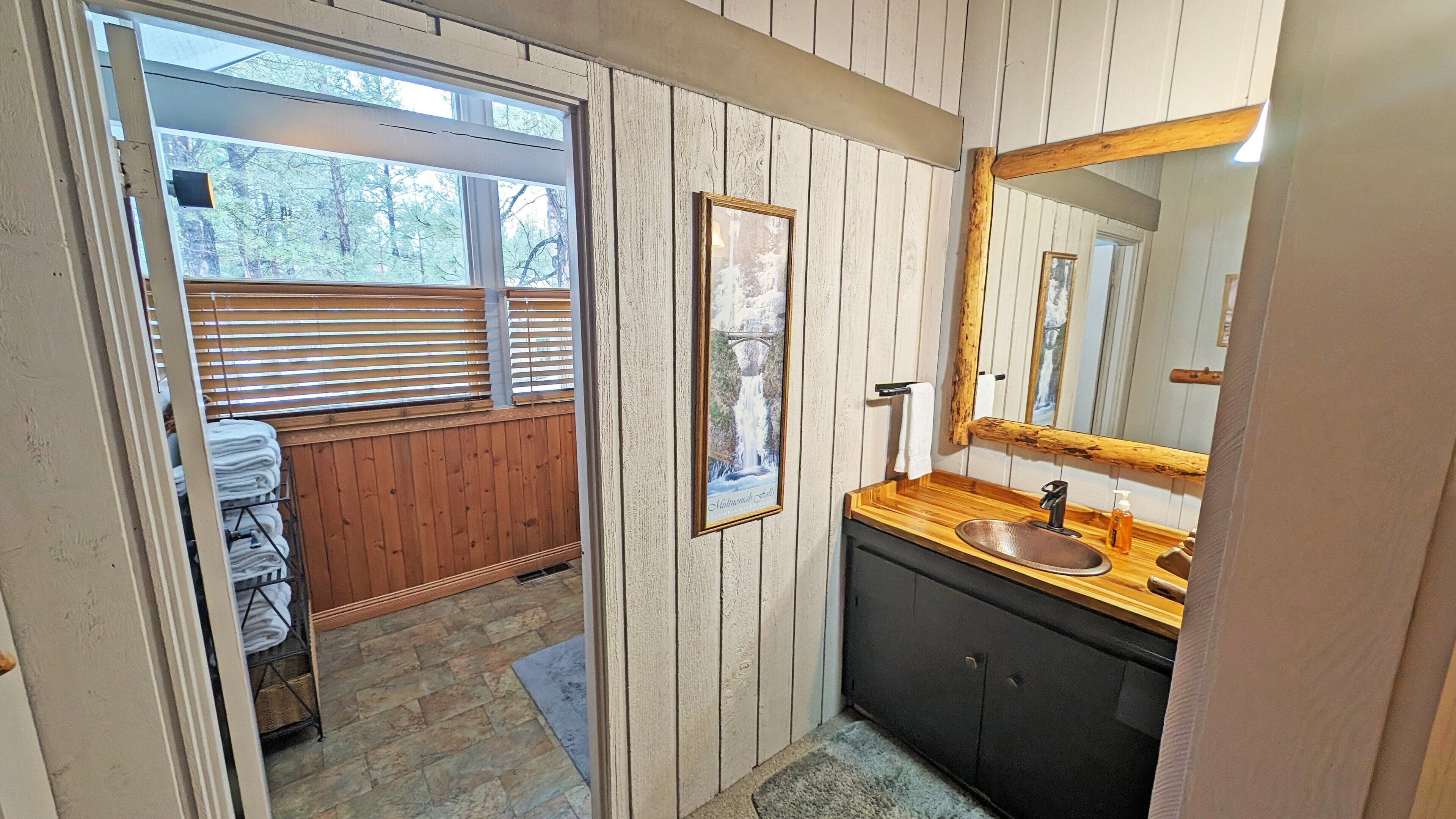 A bathroom with a wooden vanity, a sink, a mirror, and a framed picture on the wall.