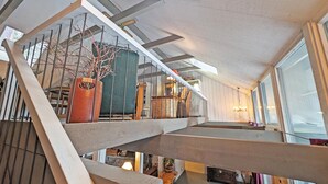 En interiör med flera nivåer, en trappa, en krukväxt och en kristallkrona.