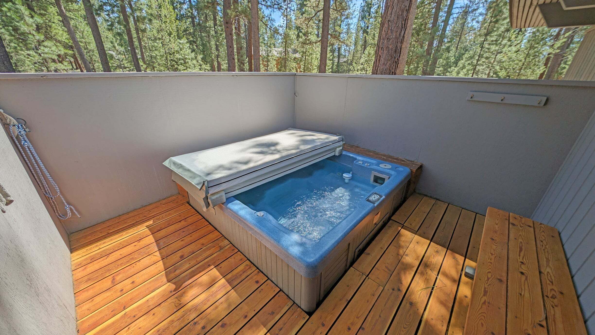 Un jacuzzi en una terraza de madera con vistas a árboles.