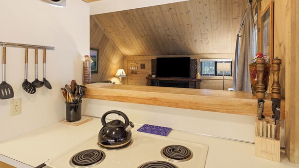 A kitchen with a stove, kettle, and knife block.