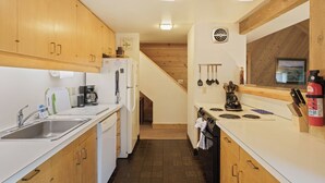 A kitchen with wooden cabinets, a white refrigerator, a stove, and a sink.
