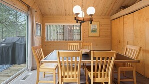 A wooden interior with a dining table and chairs, a chandelier, and framed artwork on the walls.