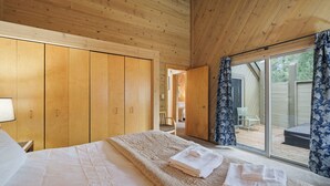 A bedroom with a large bed, wooden wardrobe, and a sliding glass door leading to an outdoor area.