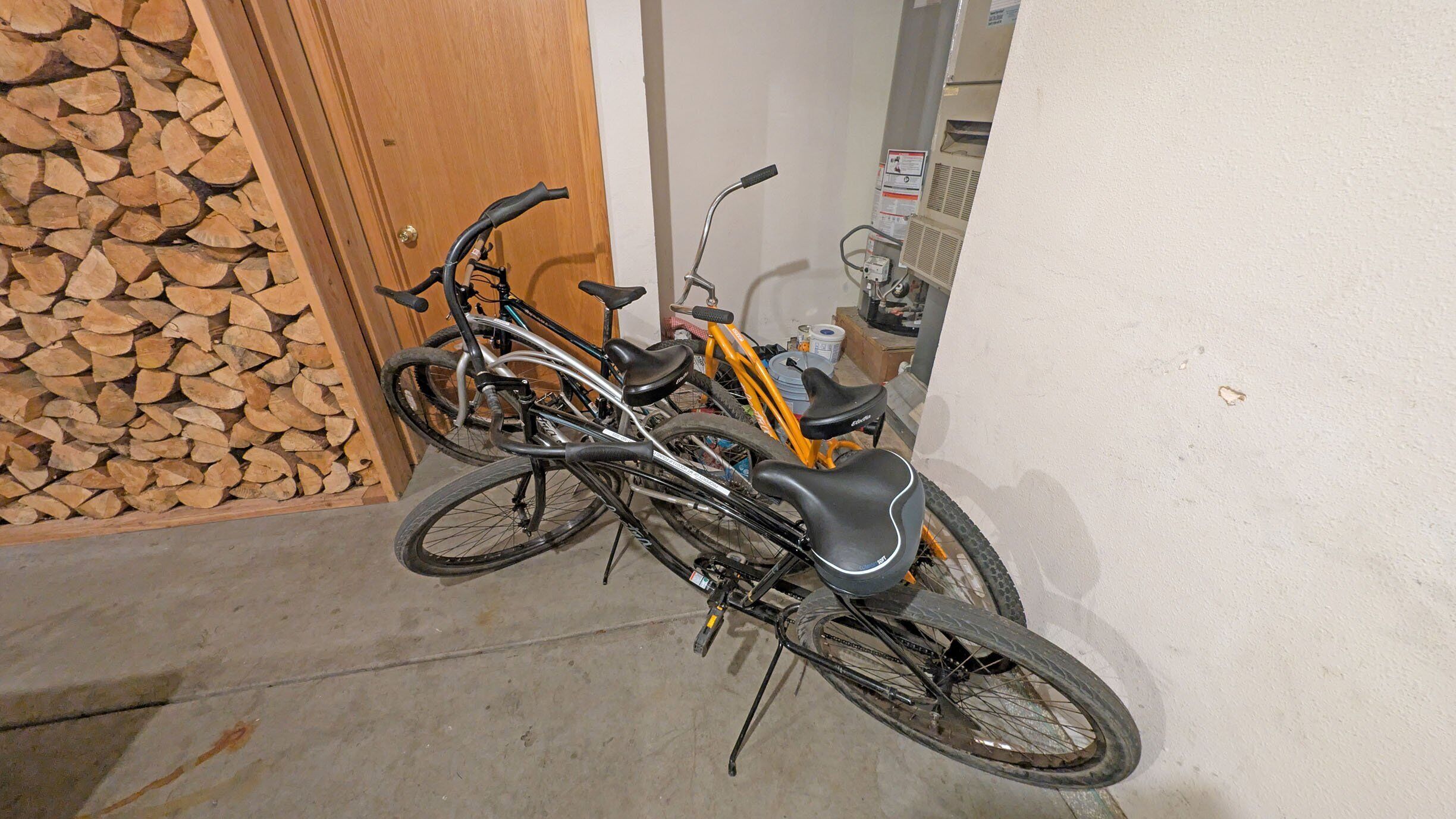Two bicycles parked indoors, a wooden door, and a wall with a fire extinguisher.