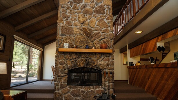 Una chimenea de piedra con repisa de madera, un banco de madera y una encimera de madera con estante.