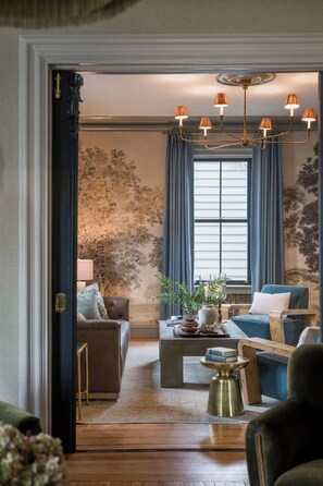 Een woonkamer met een bank, fauteuils, een salontafel en een kroonluchter.