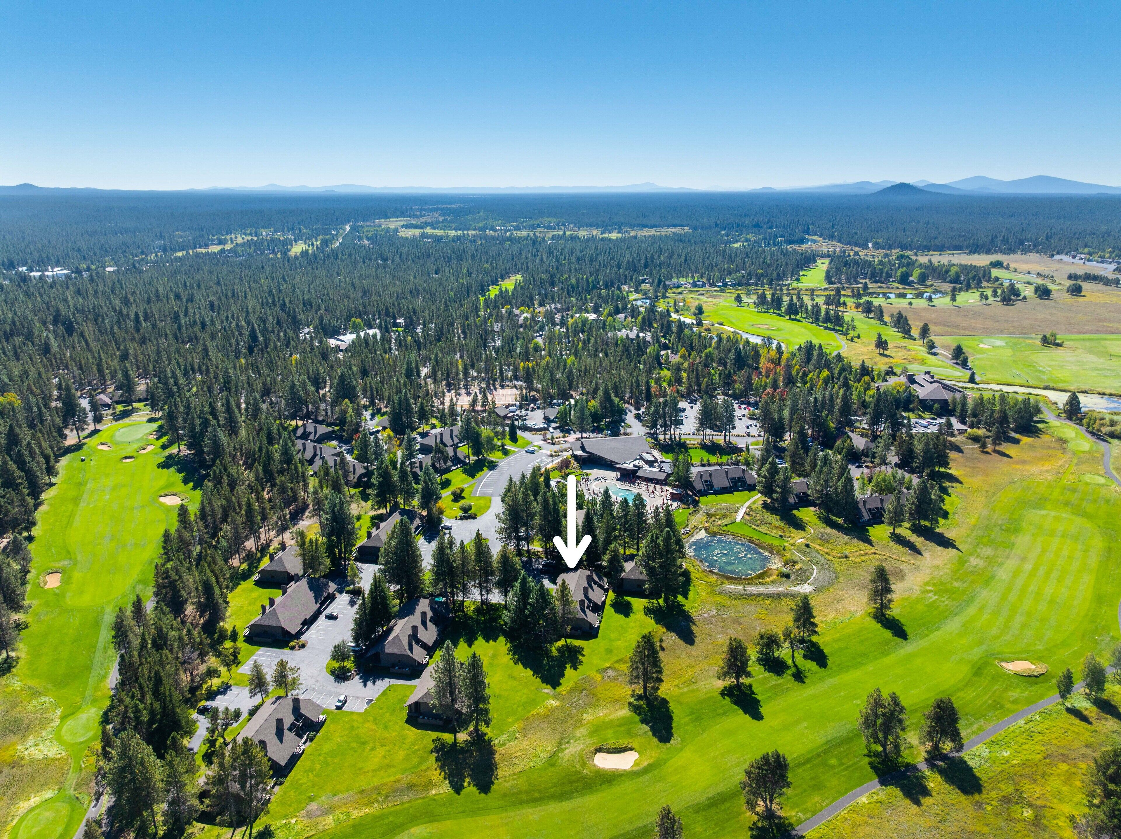 An aerial view of a golf resort with multiple buildings, a golf course, and surrounding forested areas.