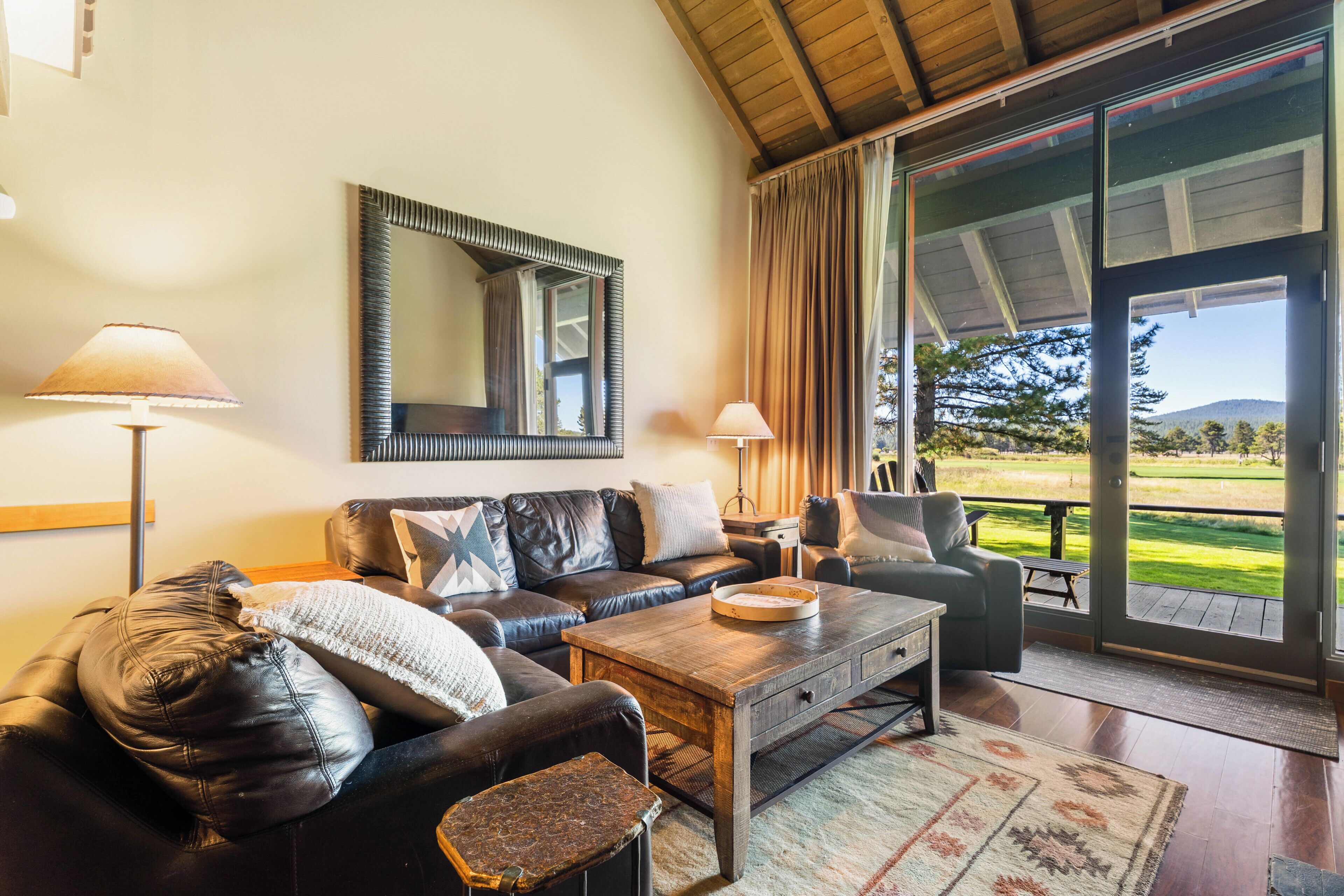 A cozy living room with a leather sofa, a wooden coffee table, and a large mirror.
