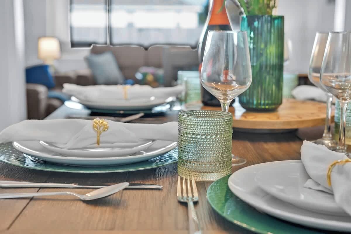 Una mesa de comedor servida con platos, cubiertos y una copa.