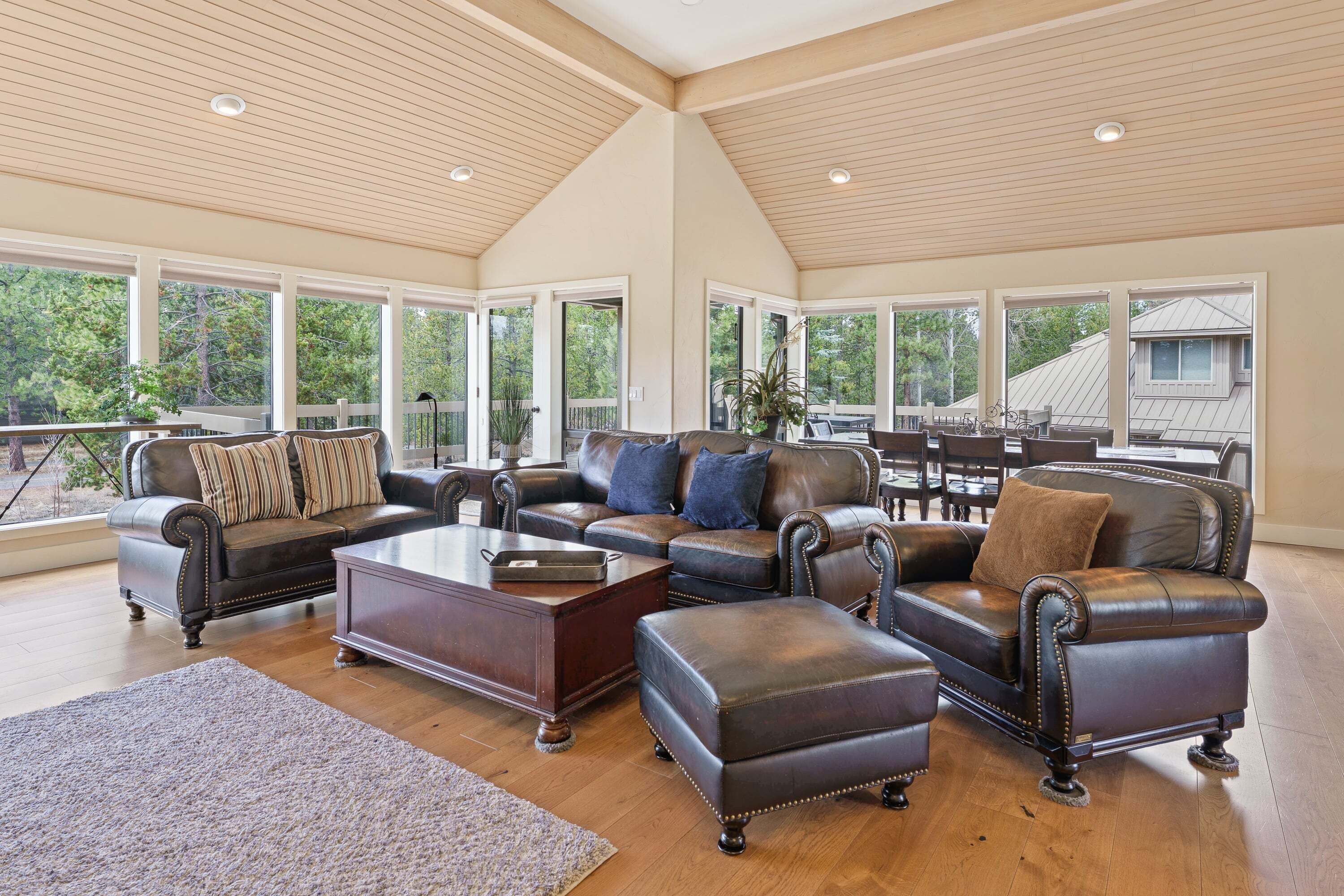A spacious living room with leather furniture, large windows, and a high ceiling.