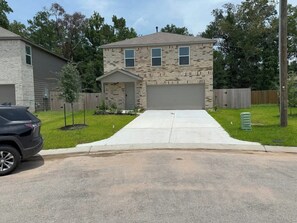 A two-story house with a garage, a driveway, and a lawn.