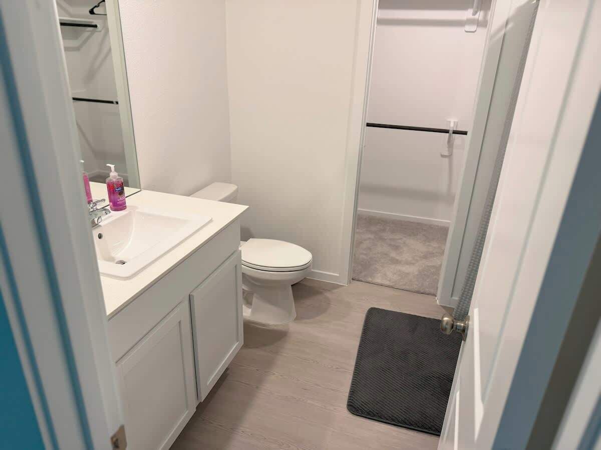A compact bathroom with a white sink, toilet, and shower area.